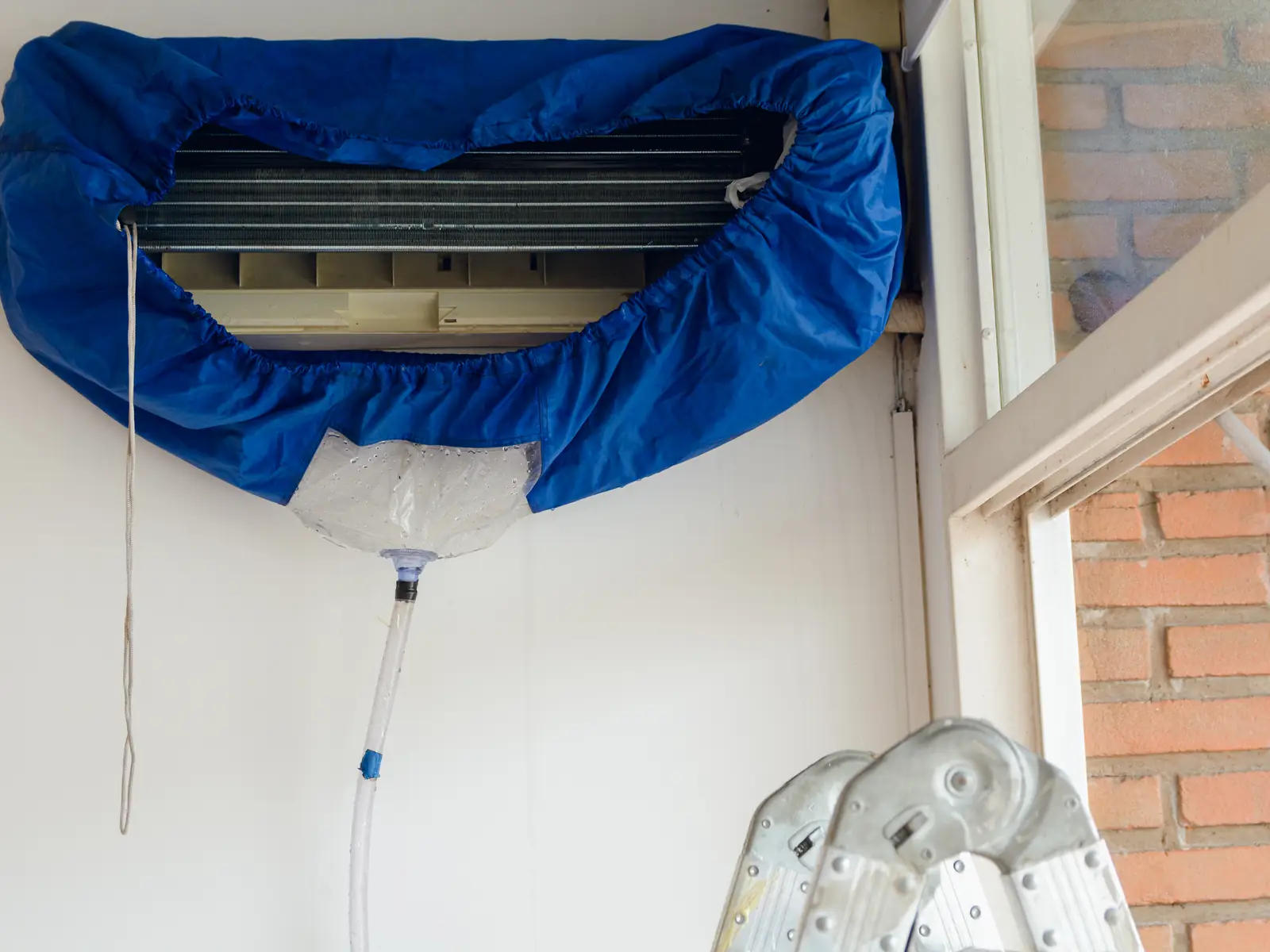 Housse de lavage installée sous une climatisation murale avant le nettoyage de l'échangeur