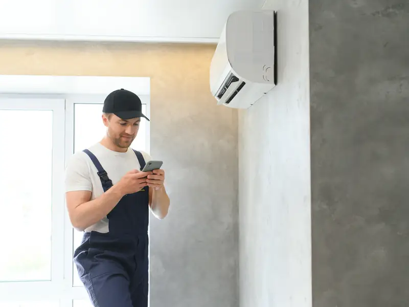 Installateur vérifiant une climatisation murale fraîchement posée