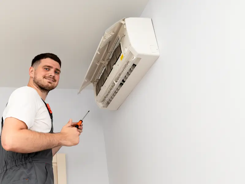 Technicien démontant une unité intérieure de climatisation pour la contrôler