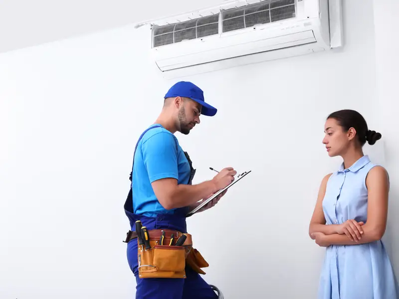 Le technicien explique à une cliente l'origine de la panne de son climatiseur