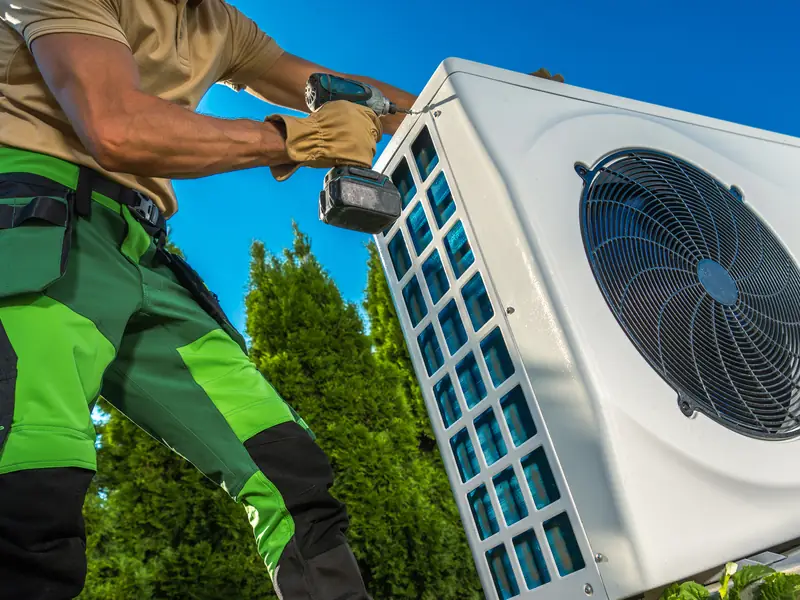 Technicien installant le groupe extérieur d'une climatisation réversible