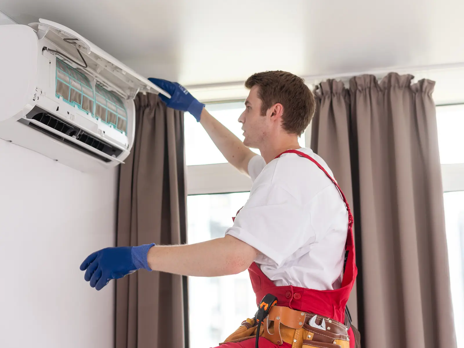 Technicien en intervention de dépannage sur une climatisation installée dans un séjour