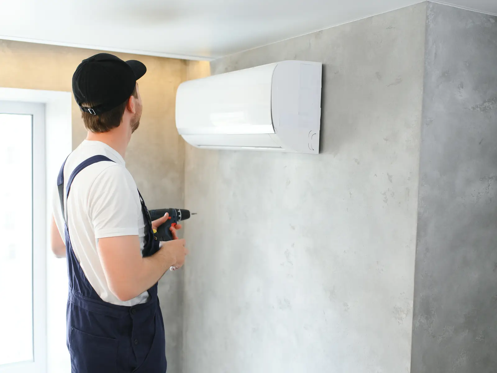 Technicien posant une unité murale de climatisation dans une maison à Cannes