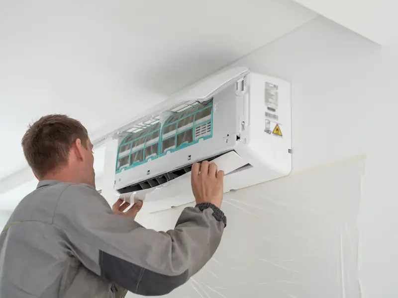 Technicien réalisant l'entretien d'un split mural de climatisation