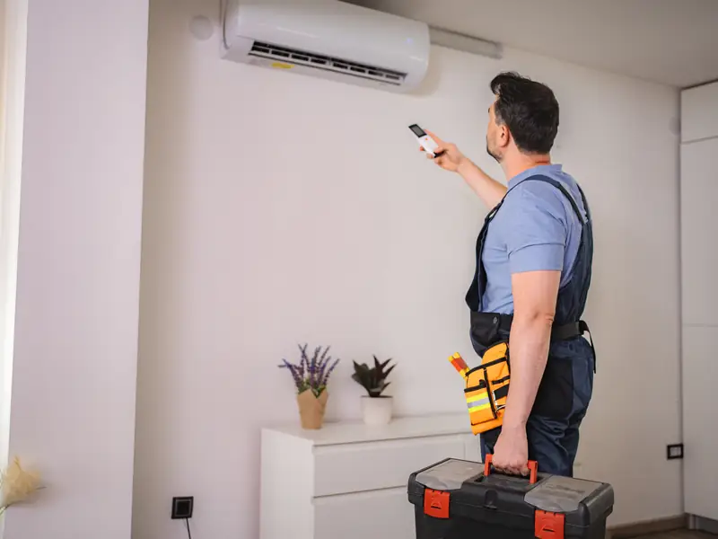 Technicien testant une climatisation à la télécommande après une réparation