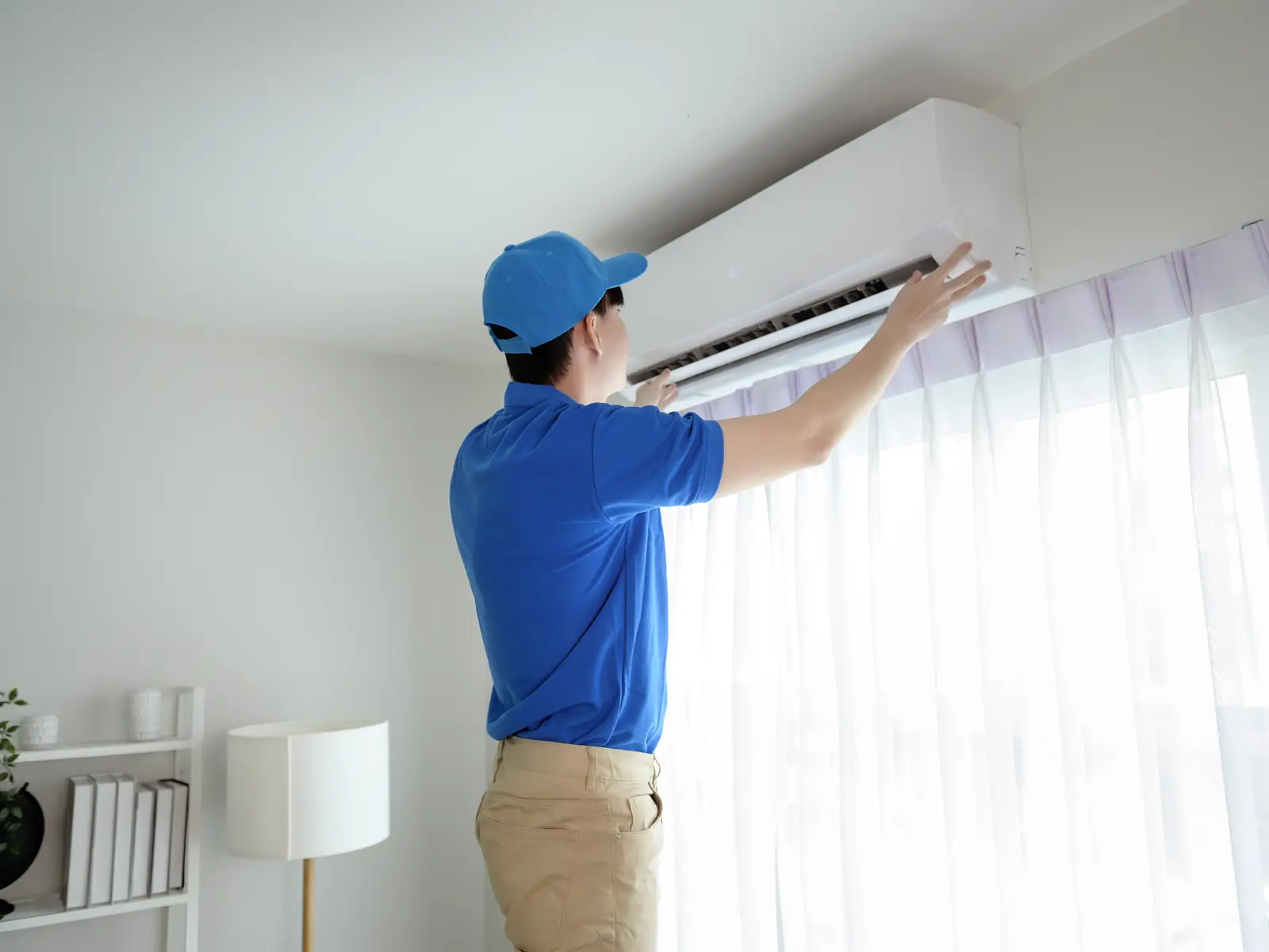 Technicien vérifiant une unité murale de climatisation à l'écoute d'un bruit anormal