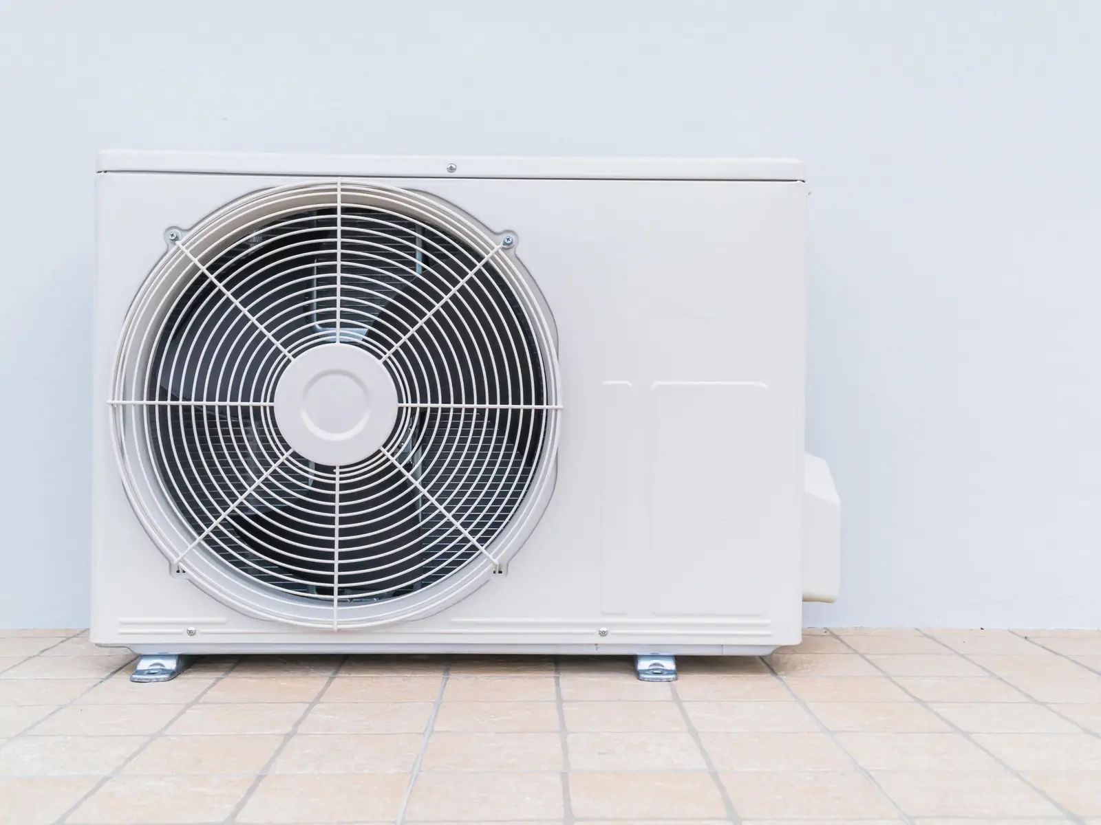 Unité extérieure de climatisation installée au sol contre une façade