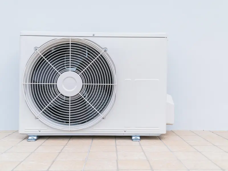 Unité extérieure de climatisation posée au sol, avec un dégagement autour de l'appareil